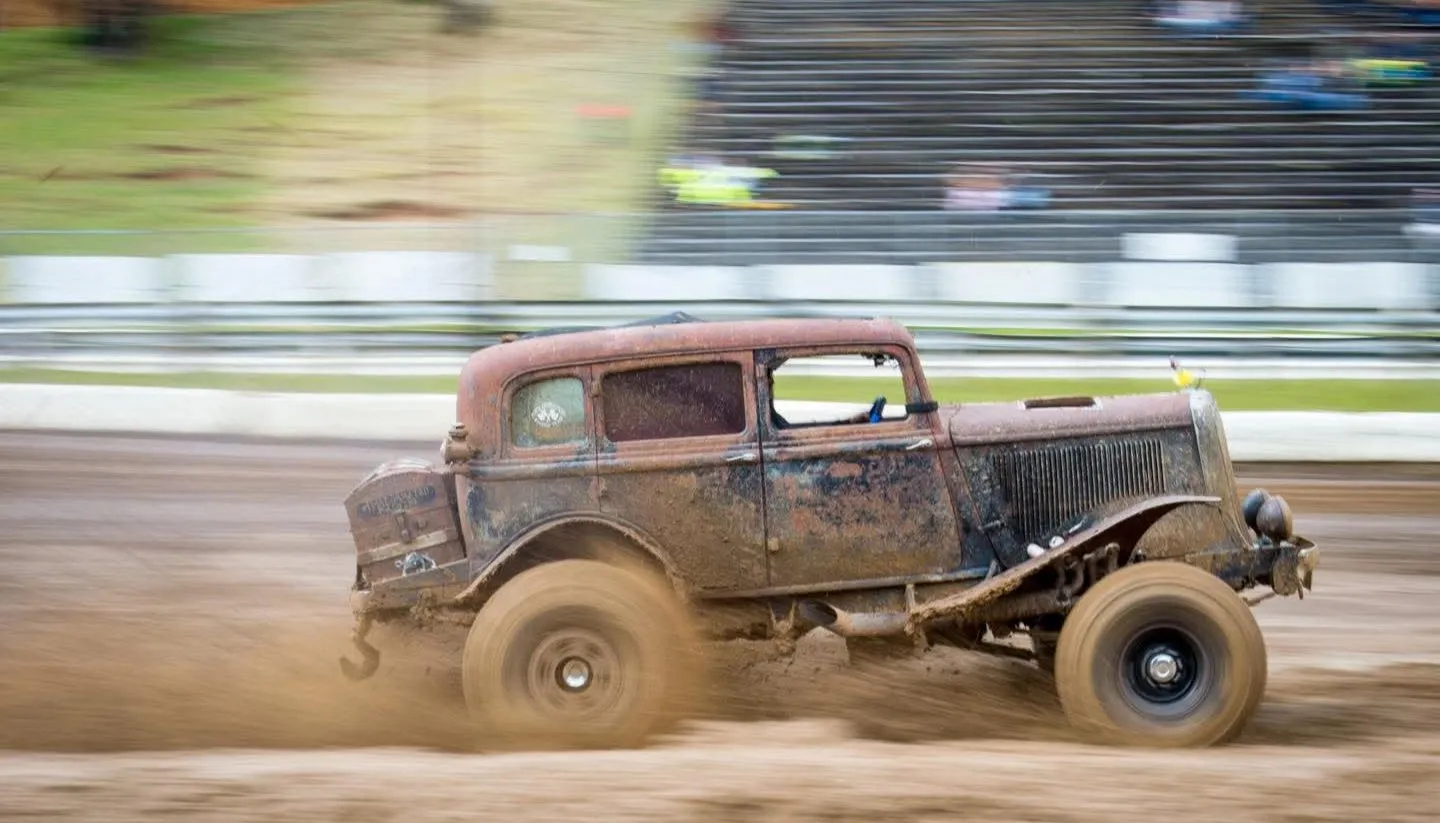 A vintage rat rod sliding through the dirt at speed